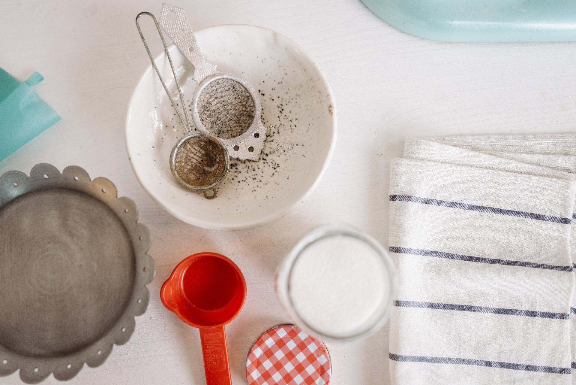 A table topped with a bowl , measuring cups , and a towel.
