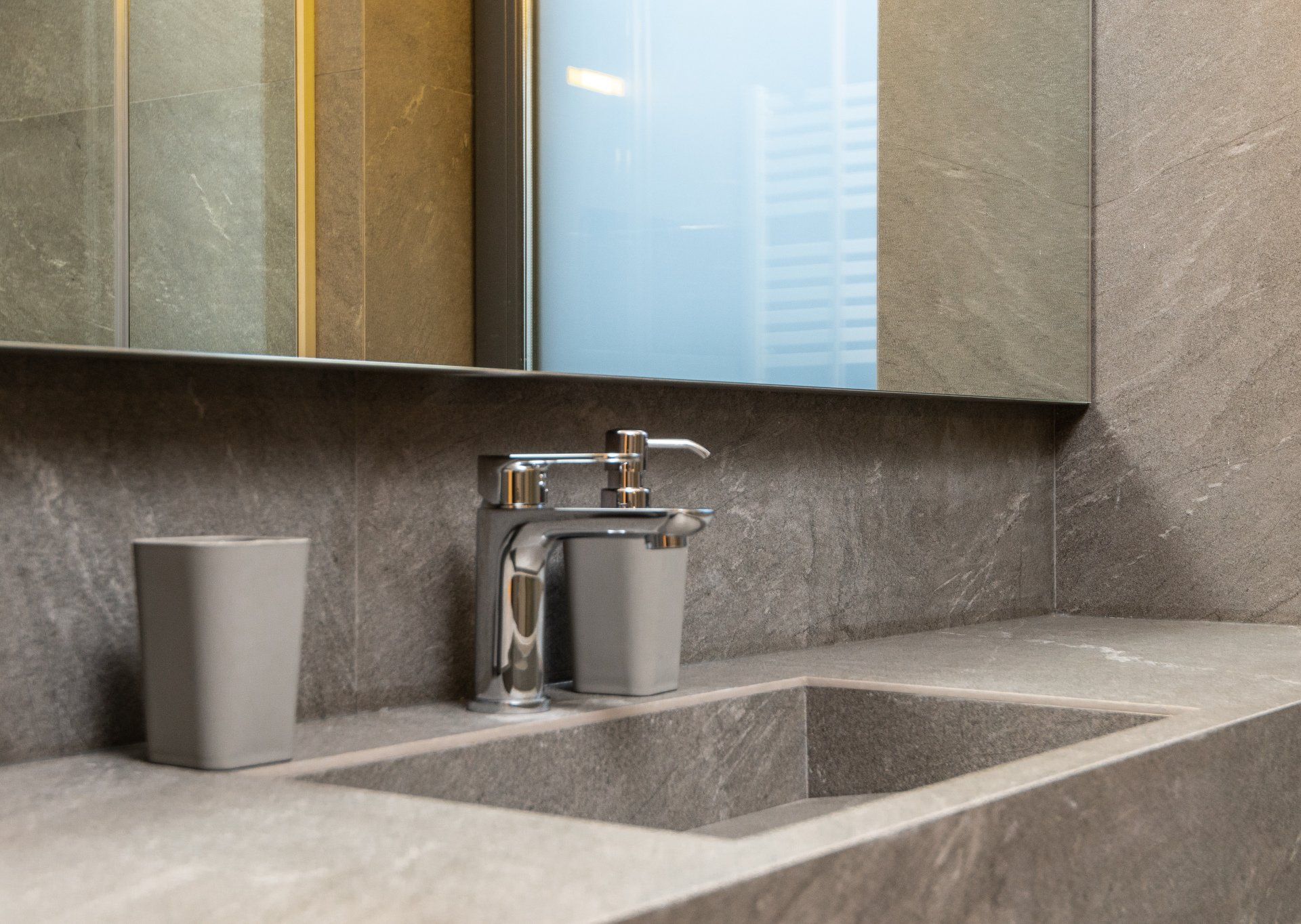 a bathroom sink with a soap dispenser and a mirror. Bathroom Remodeling Trends for 2024