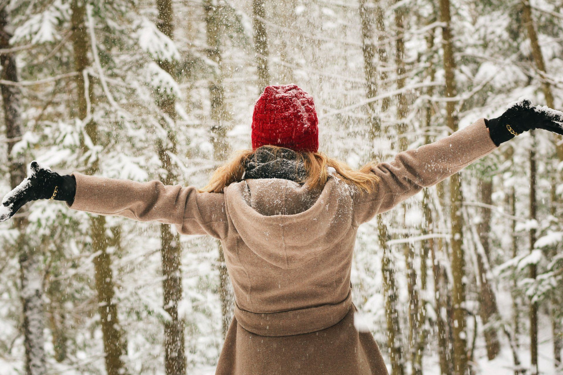 a woman wearing gloves is blowing snow into the air