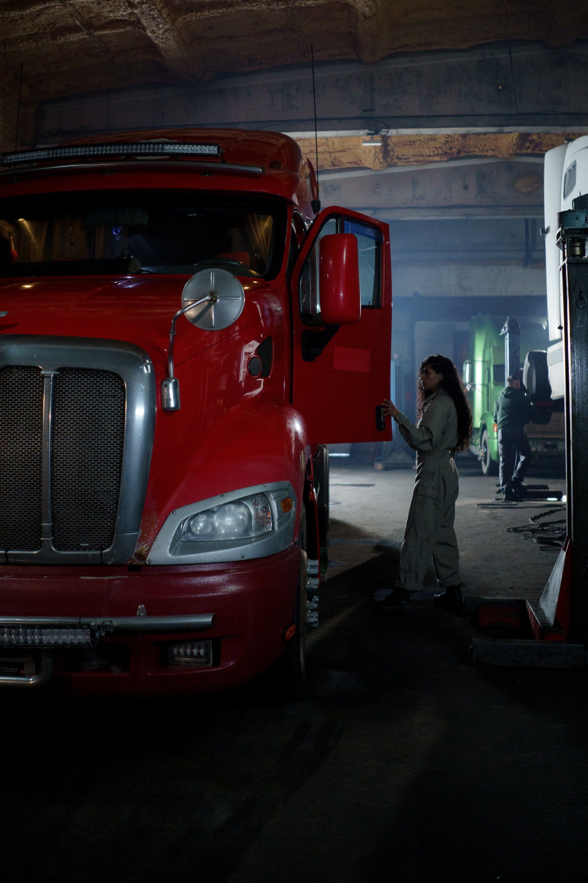 A women is climbing into her semi truck. 