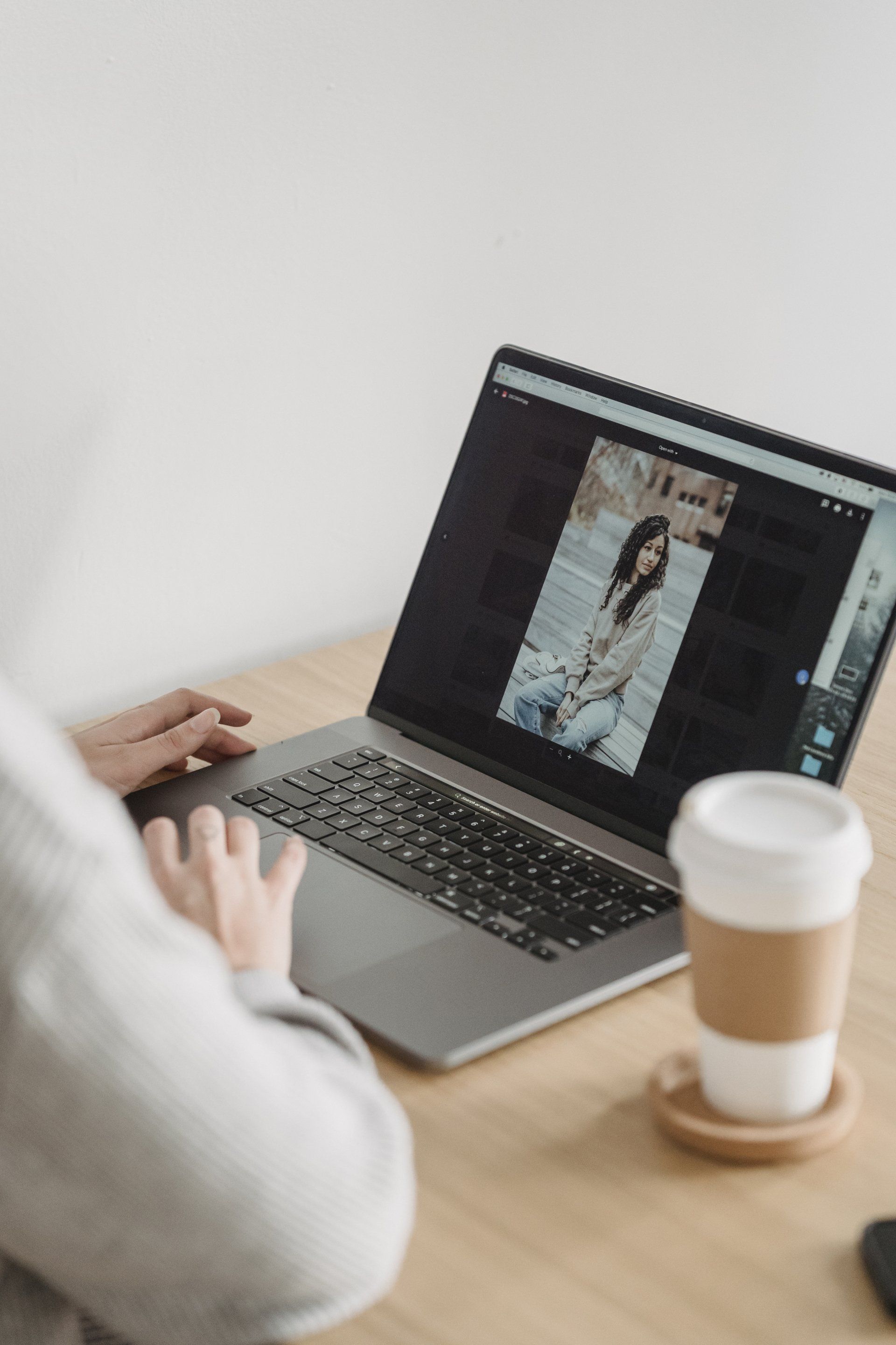 A person is using a laptop computer with a picture of a woman on the screen.