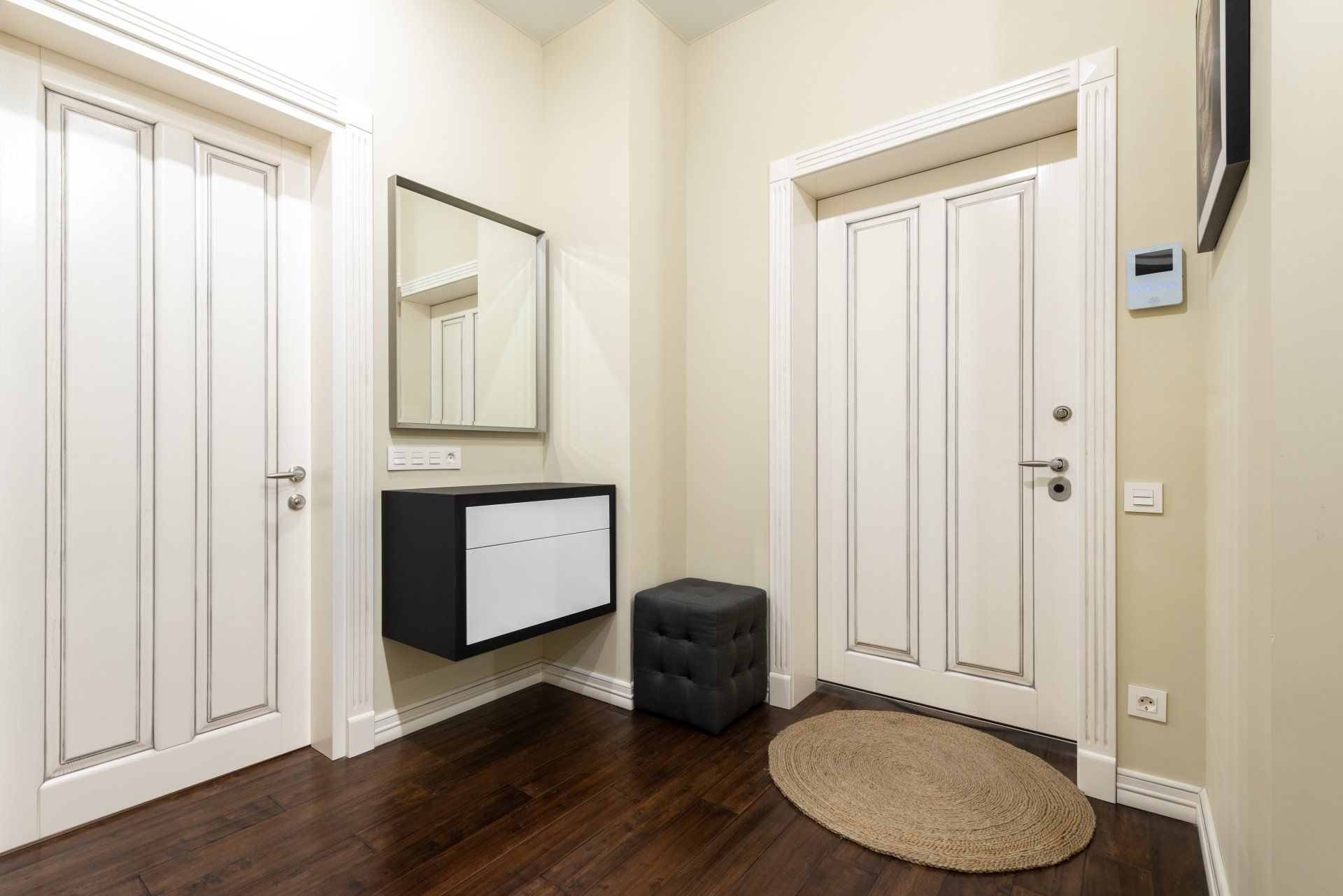 A hallway with white doors , a mirror , and a rug.