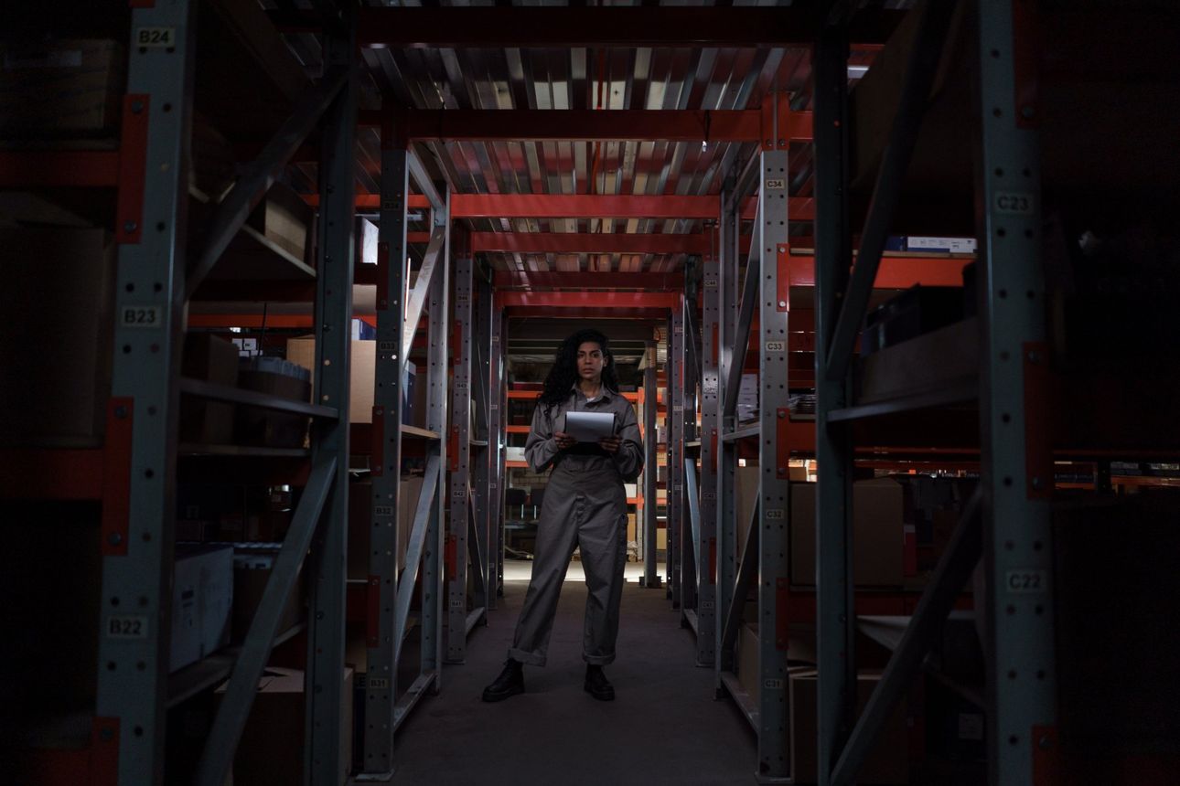 A woman is standing in a warehouse holding a tablet.