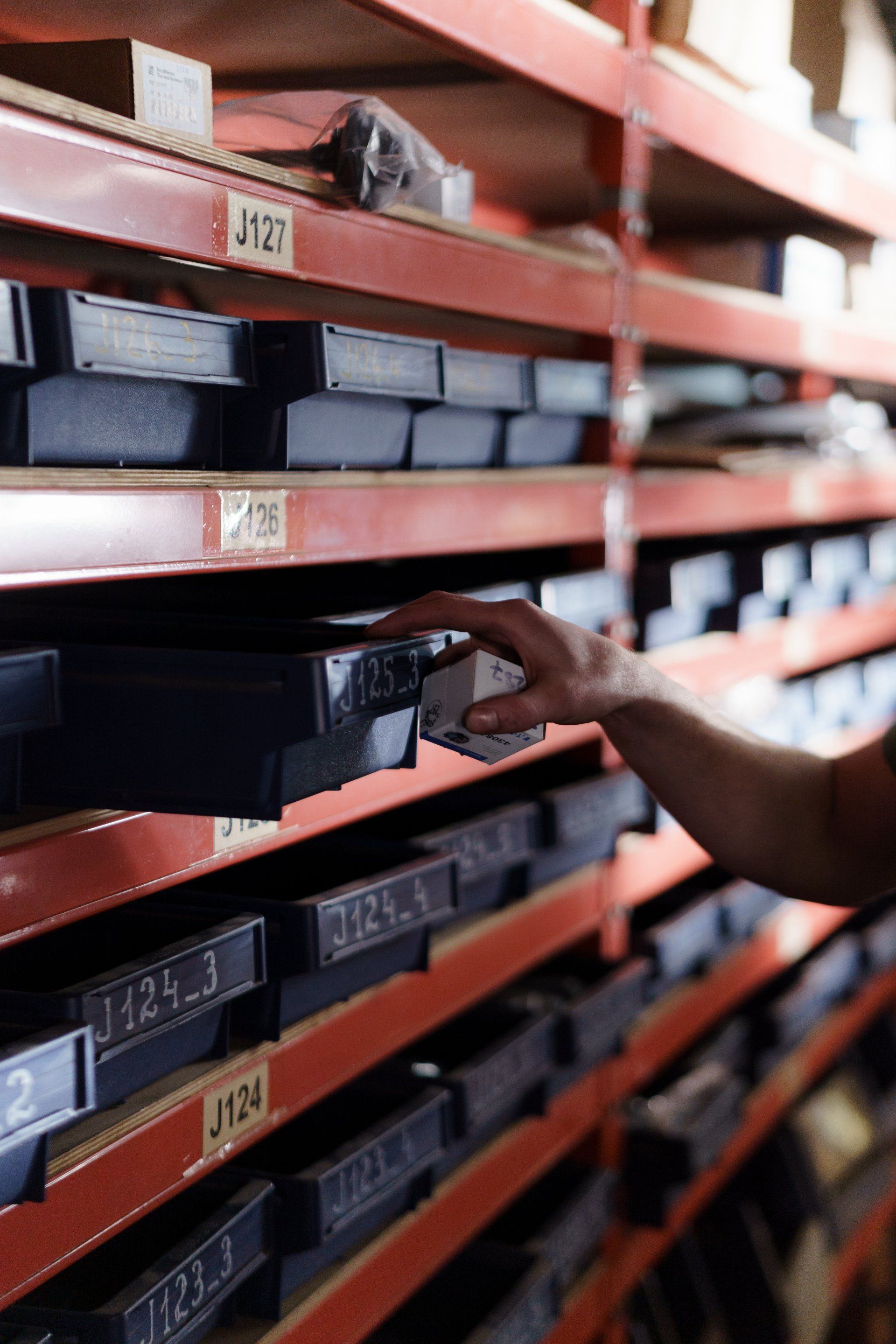 A person is reaching for a box on a shelf in a warehouse.
