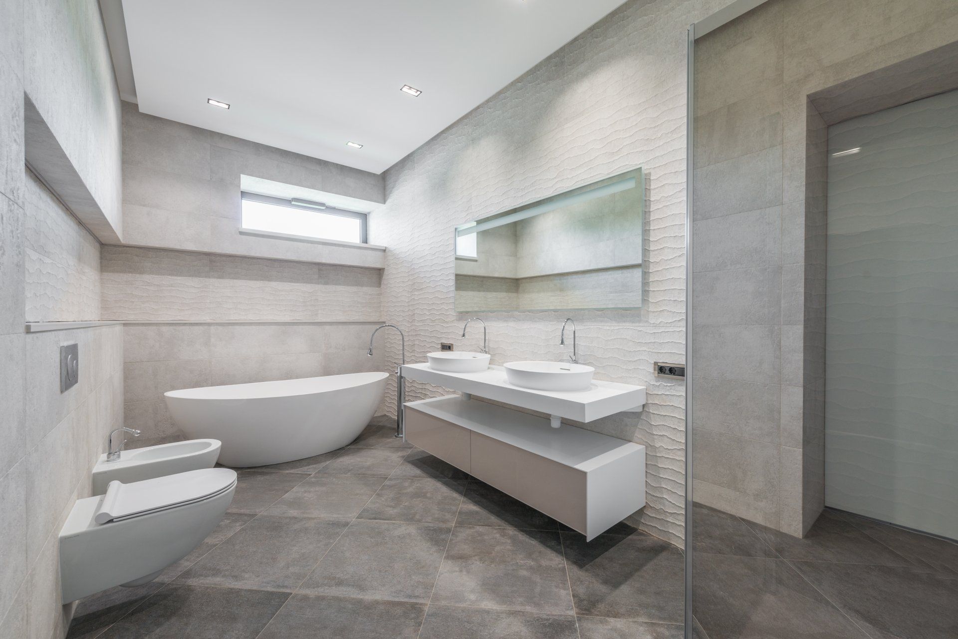 Een badkamer met ligbad, wastafel, toilet en spiegel.