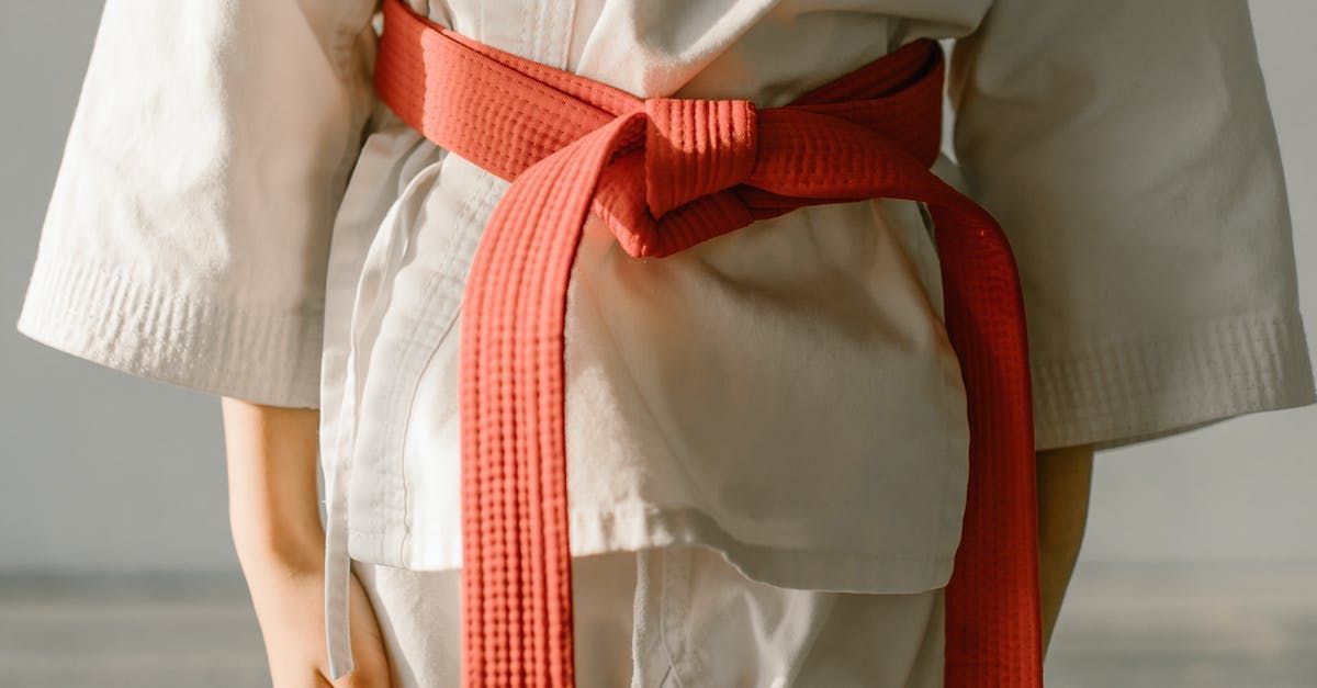 A person wearing a white karate uniform with a red belt.