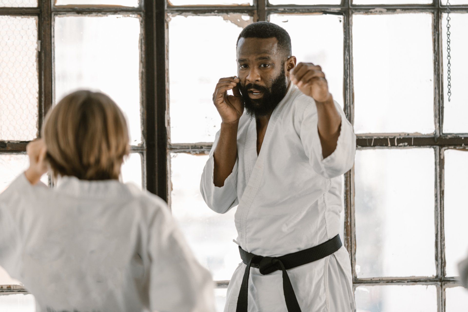 A man and a woman are practicing karate in a gym.