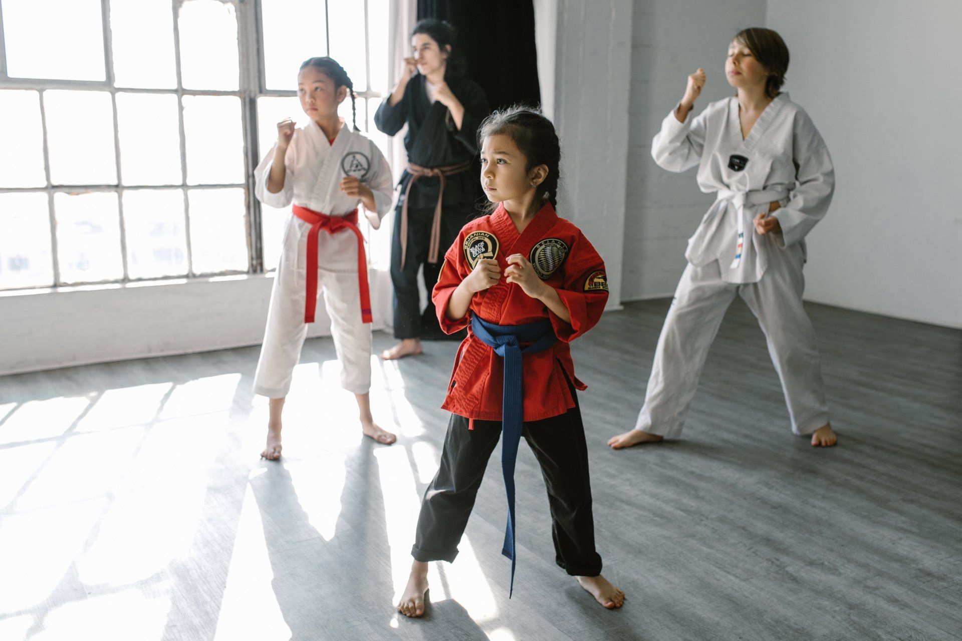 A group of young girls are practicing karate in a gym.