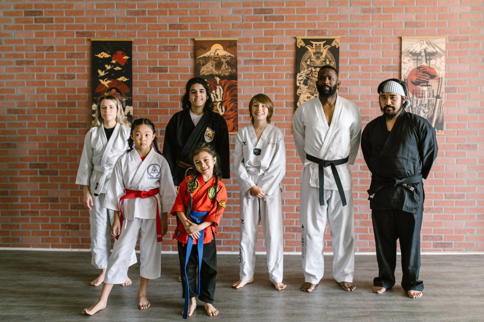a group of people in karate uniforms are standing next to each other in front of a brick wall .