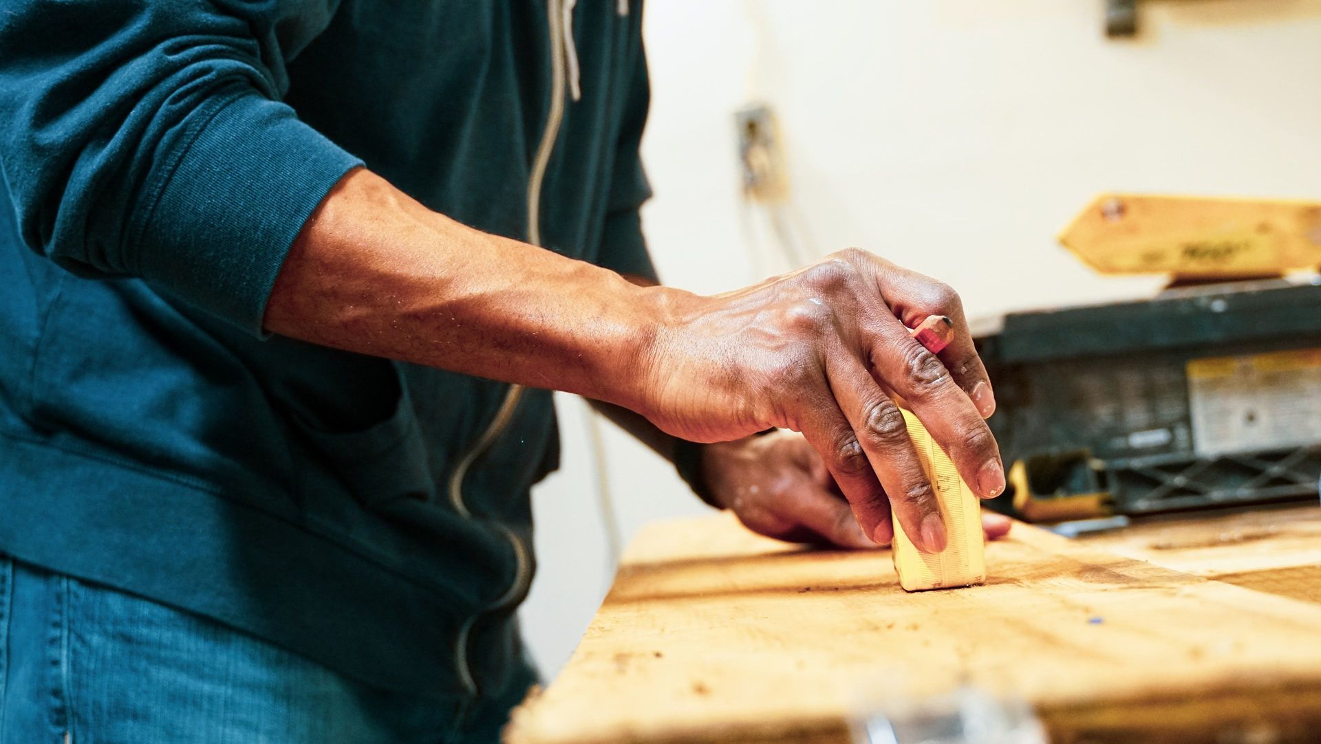A man is sanding a piece of wood with a sander.