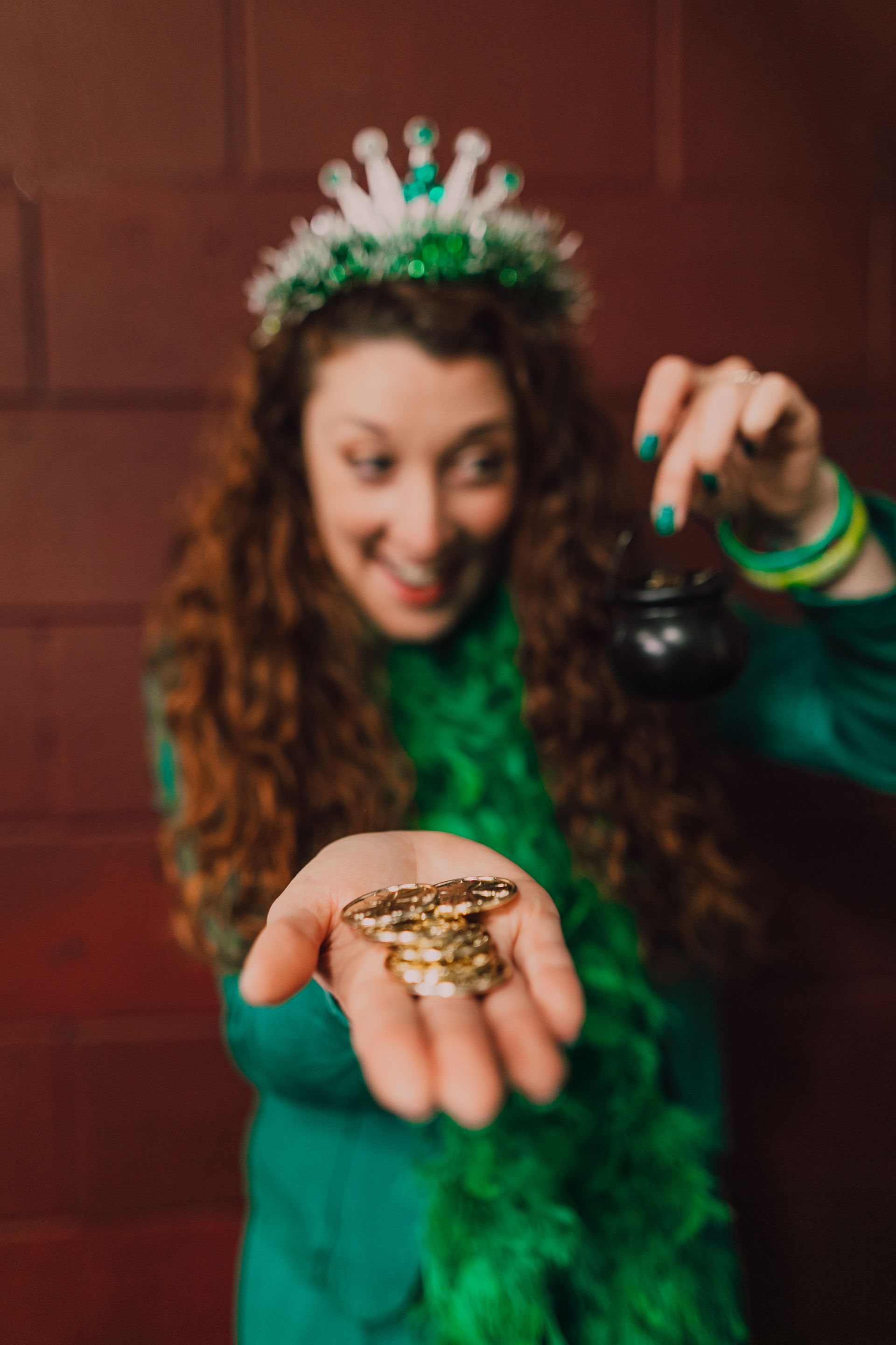 a woman in a green dress is holding a pot of gold in her hand
