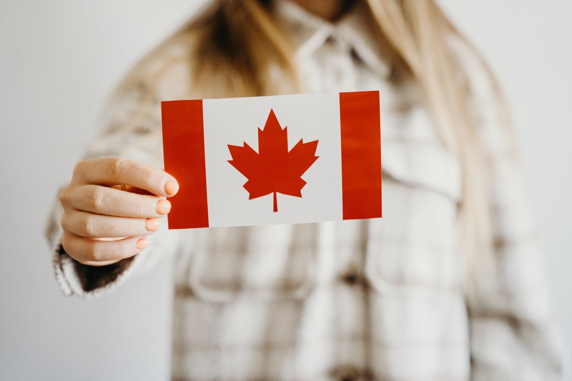 a woman is holding a small canadian flag in her hand .
