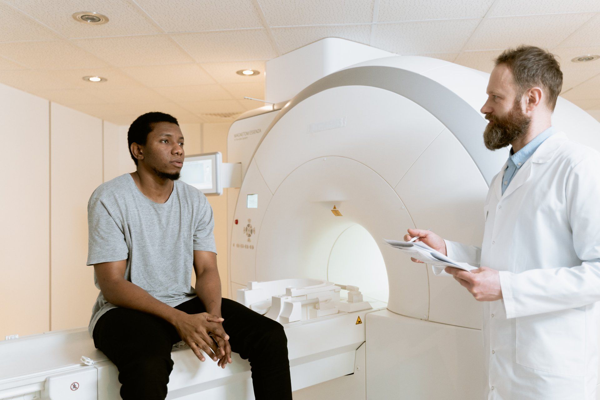 A doctor is talking to a patient sitting on a mri machine.
