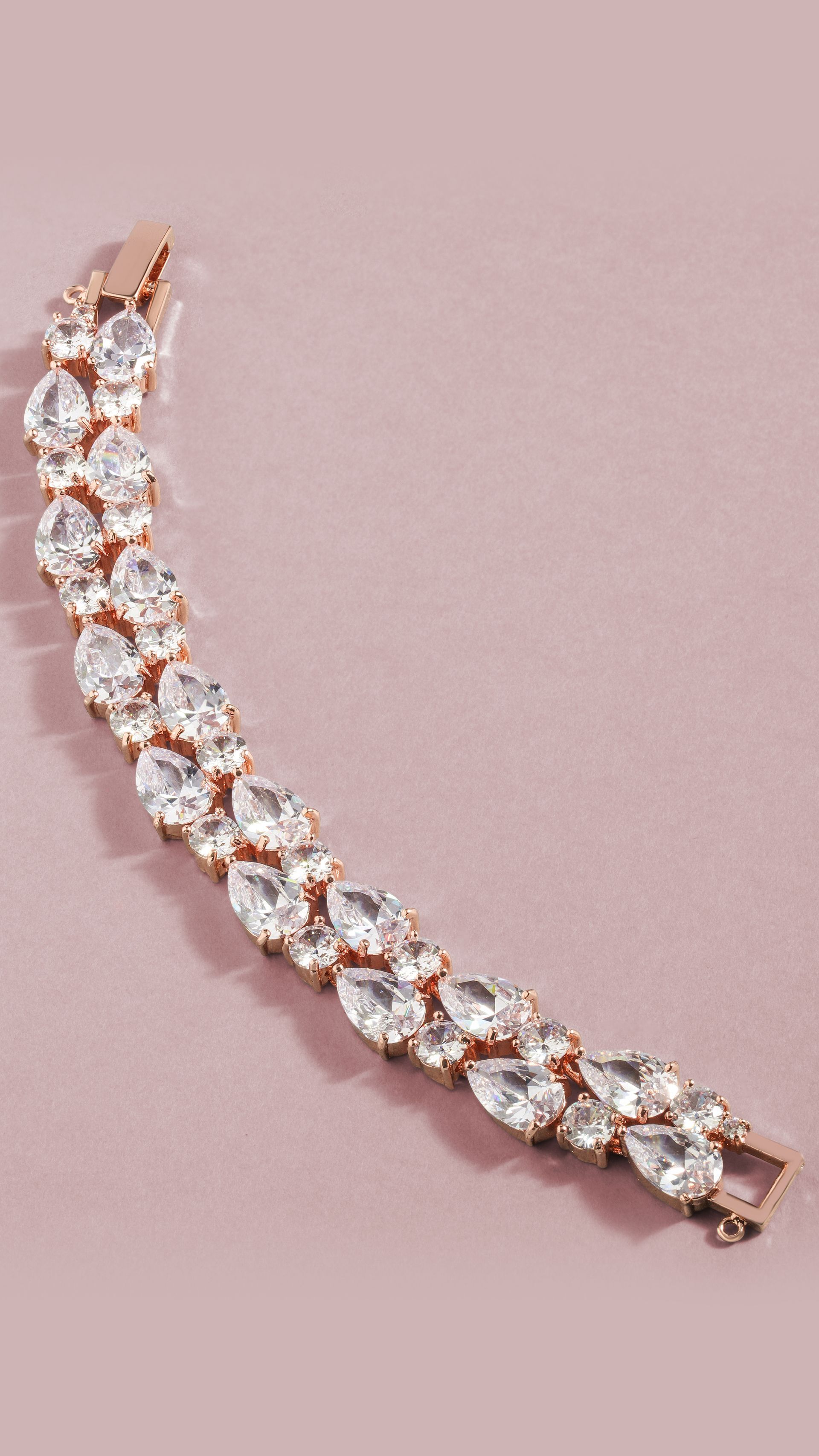 A close up of a bracelet with rhinestones on a pink surface.