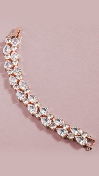 A close up of a bracelet with rhinestones on a pink surface.