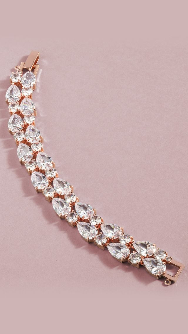 A close up of a bracelet with rhinestones on a pink surface.
