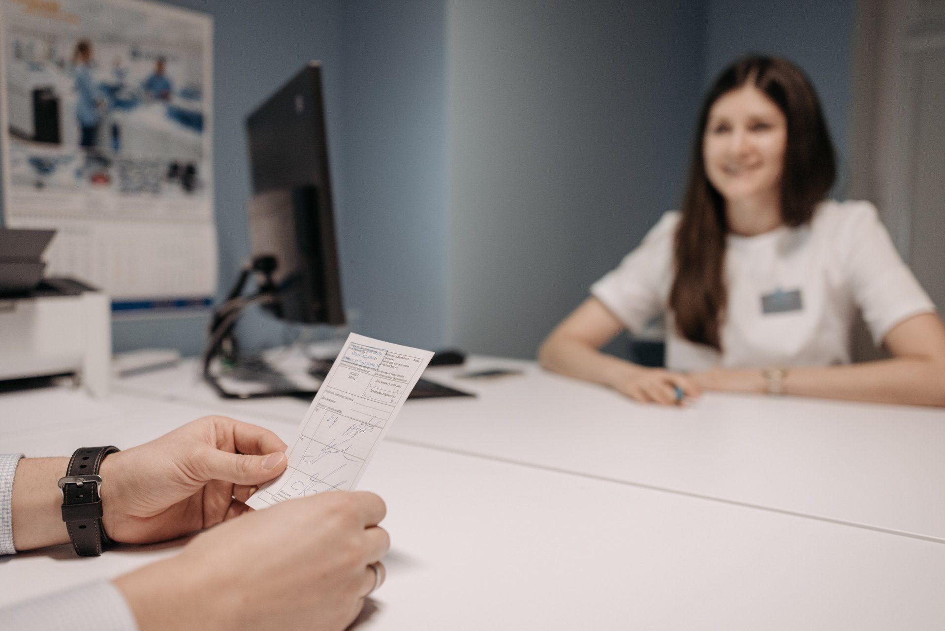 a doctor is holding the appointment paper in front of a woman sitting at a desk.
