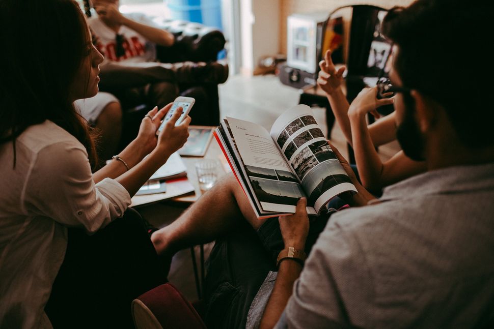 A group of people are sitting around a table reading books.