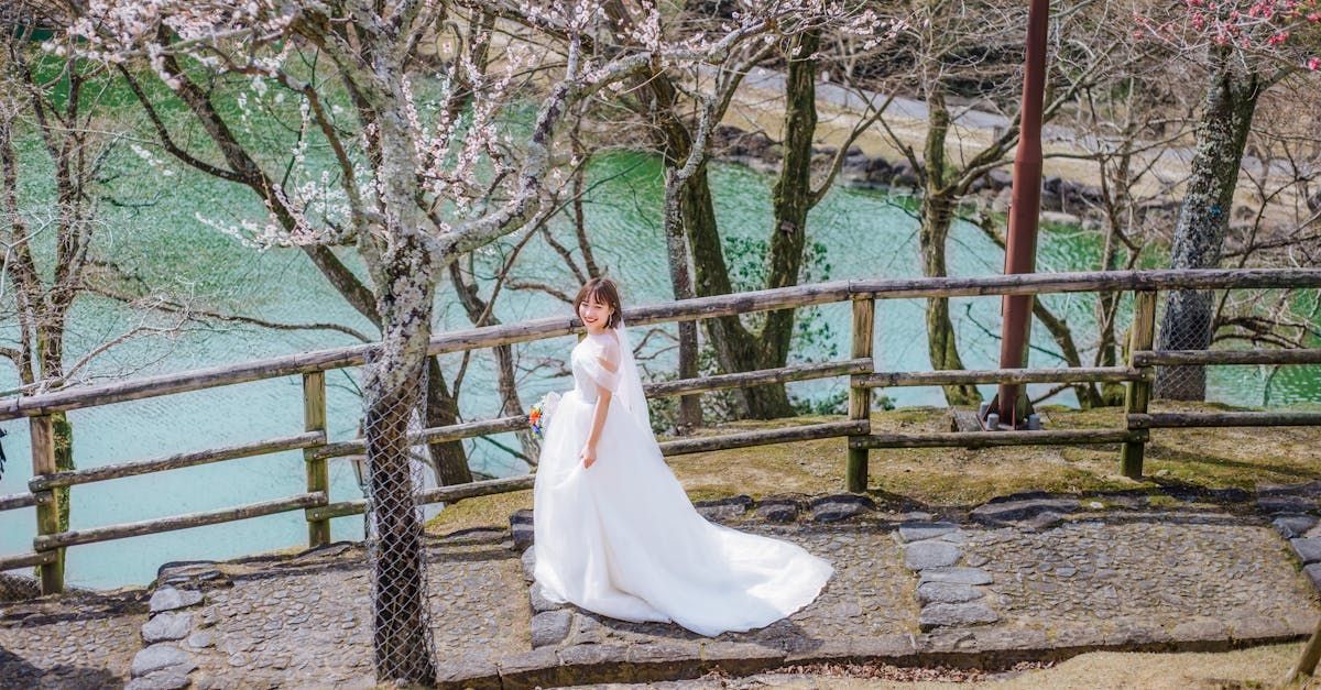 a woman in a wedding dress is standing in front of a lake .