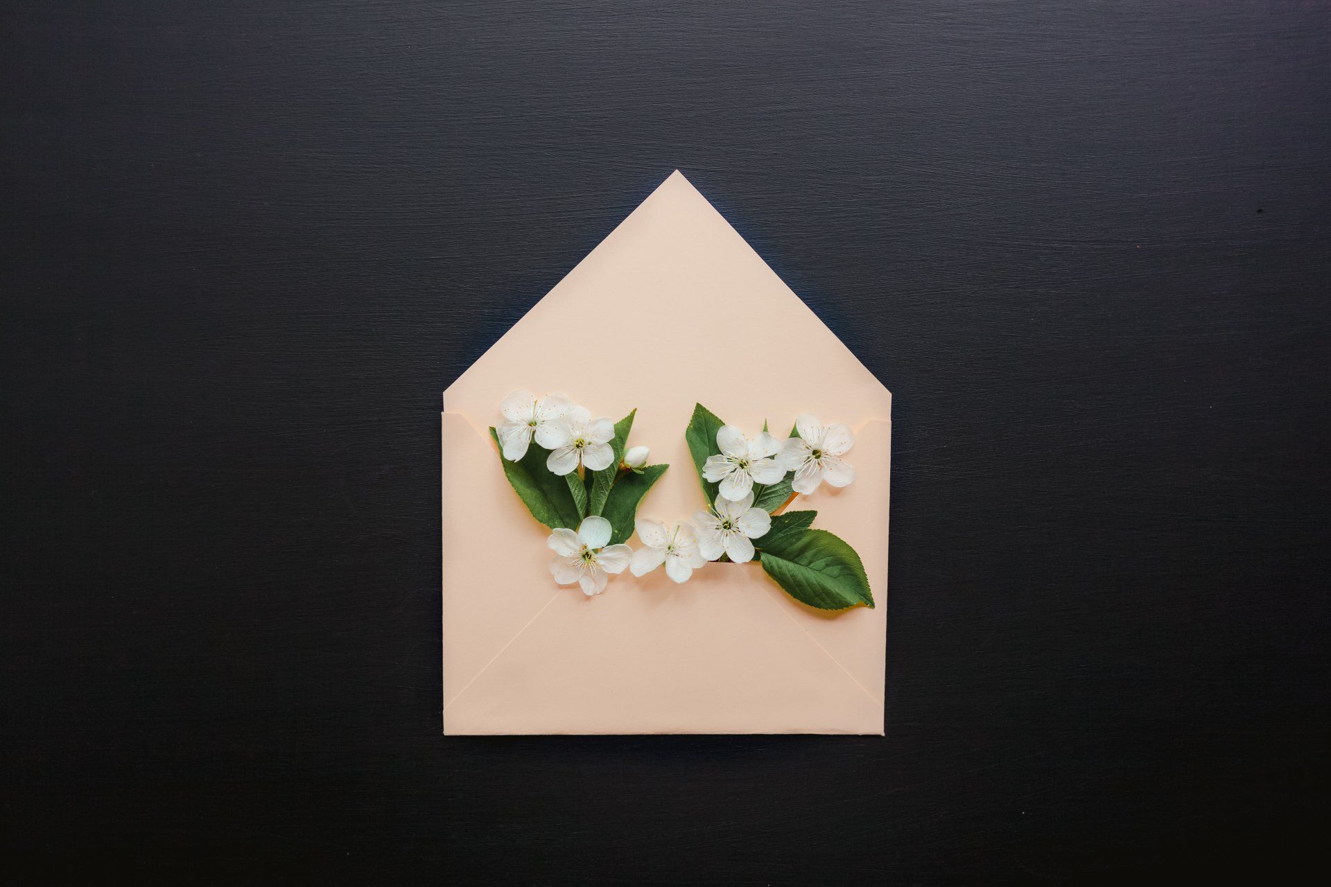 An envelope with white flowers and green leaves on a black background
