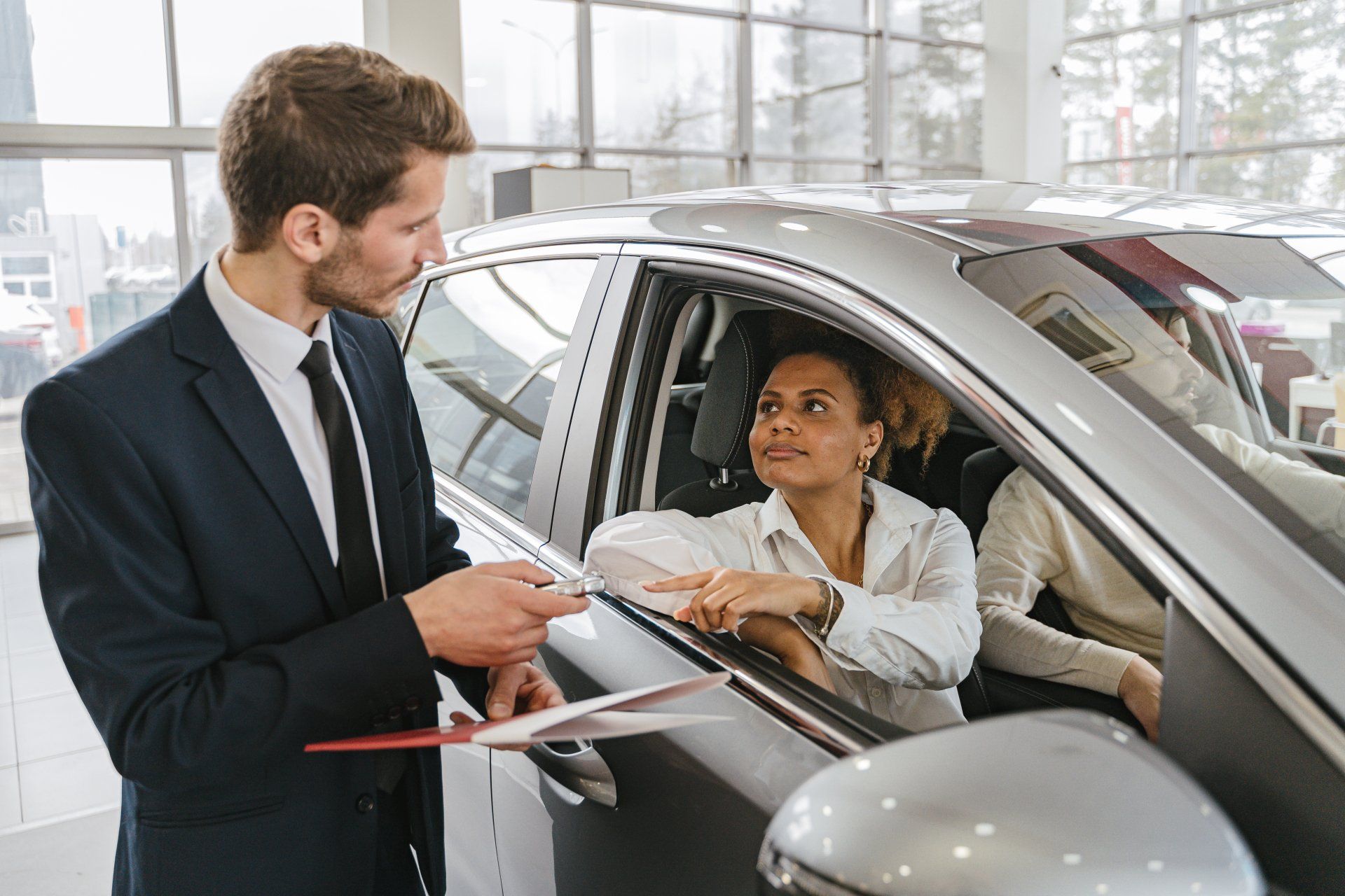 a man is talking to a woman in a car in a showroom .