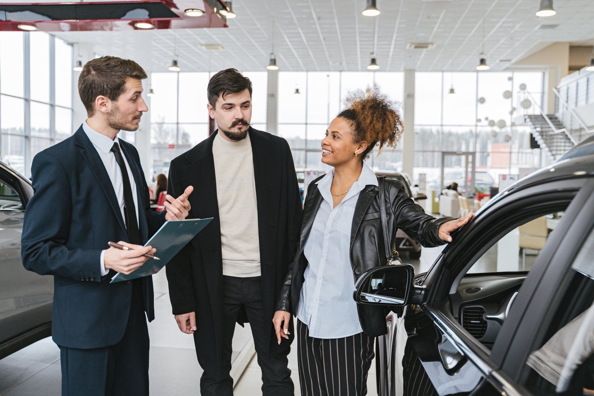 A man and a woman are looking at a car in a showroom.