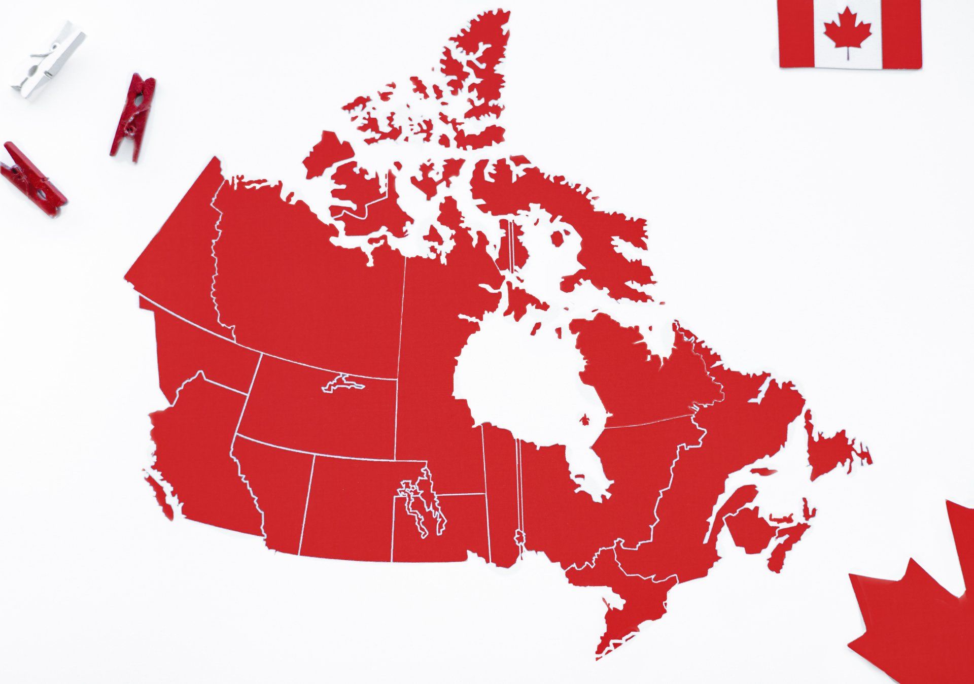 A red map of canada with a canadian flag in the background