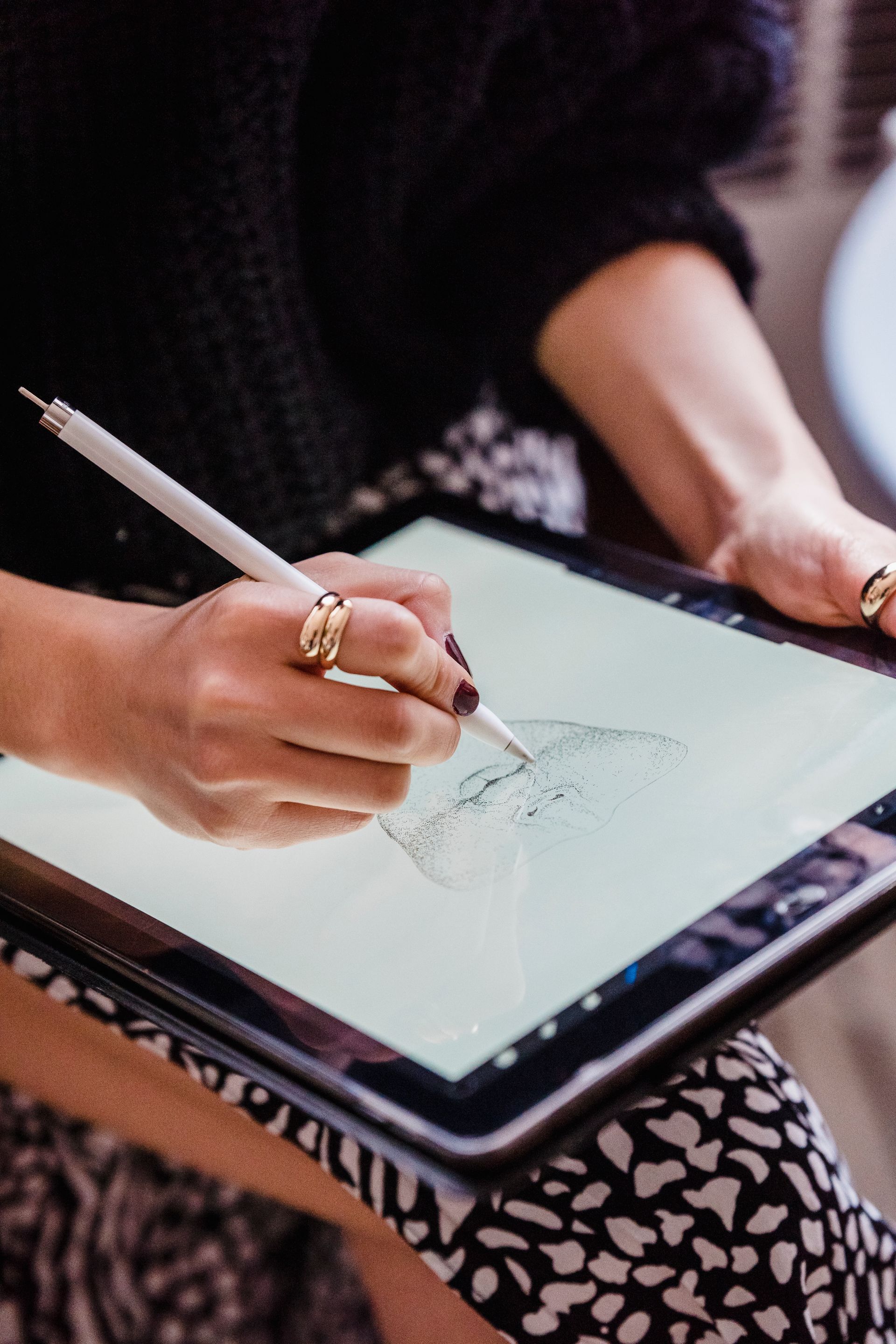 a woman is drawing on a tablet with a pen .