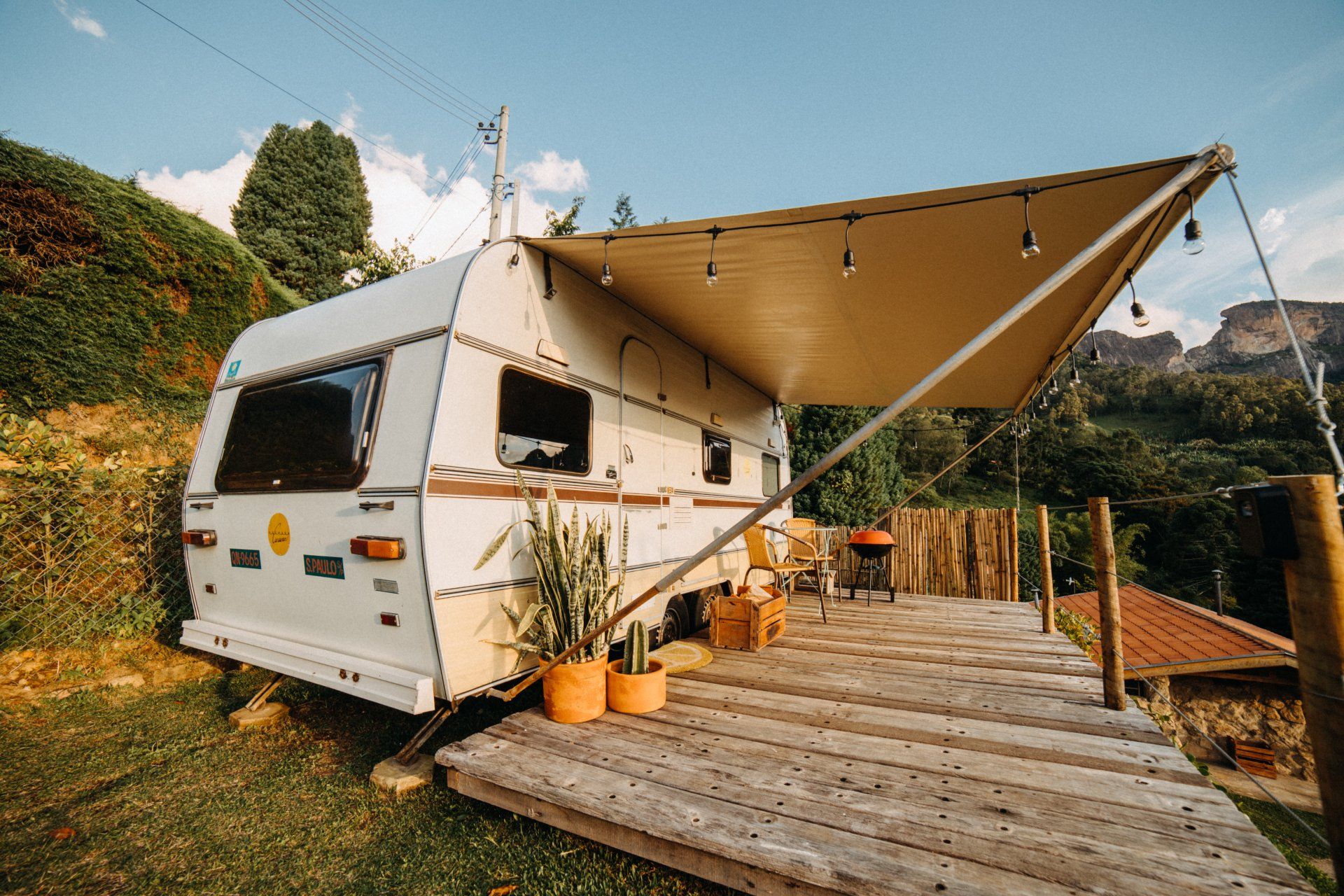 A white trailer with a canopy is parked on a wooden deck.