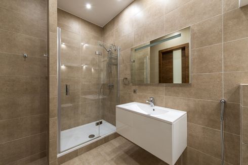 A bathroom with a sink , shower and mirror.