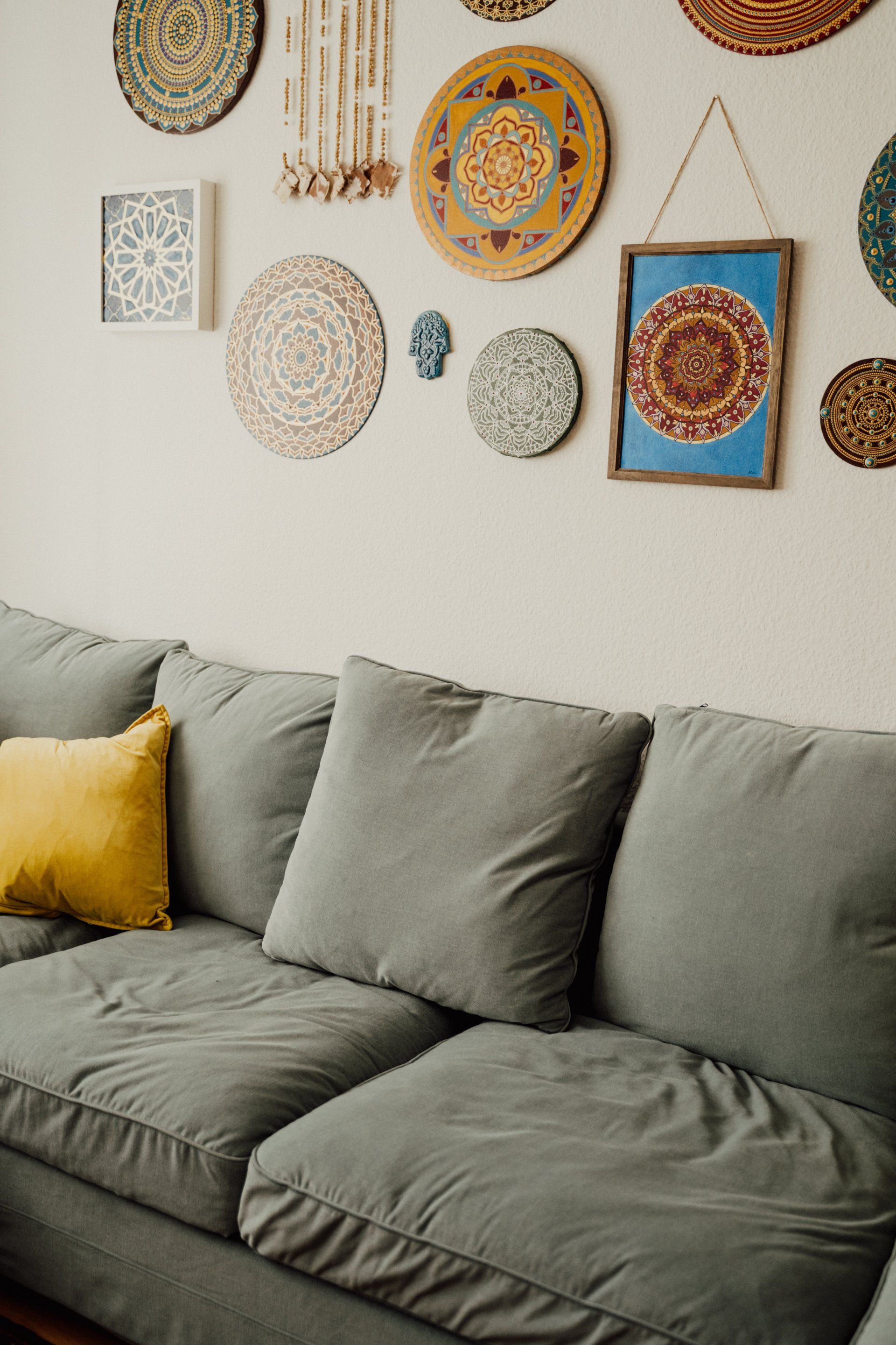 un divano appoggiato a un muro con quadri e piatti colorati
