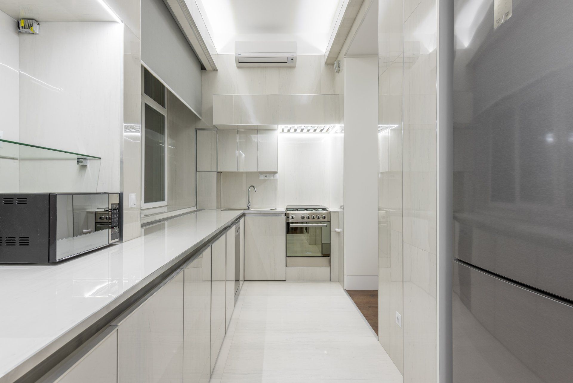 A kitchen with white cabinets , stainless steel appliances , a refrigerator and a microwave.