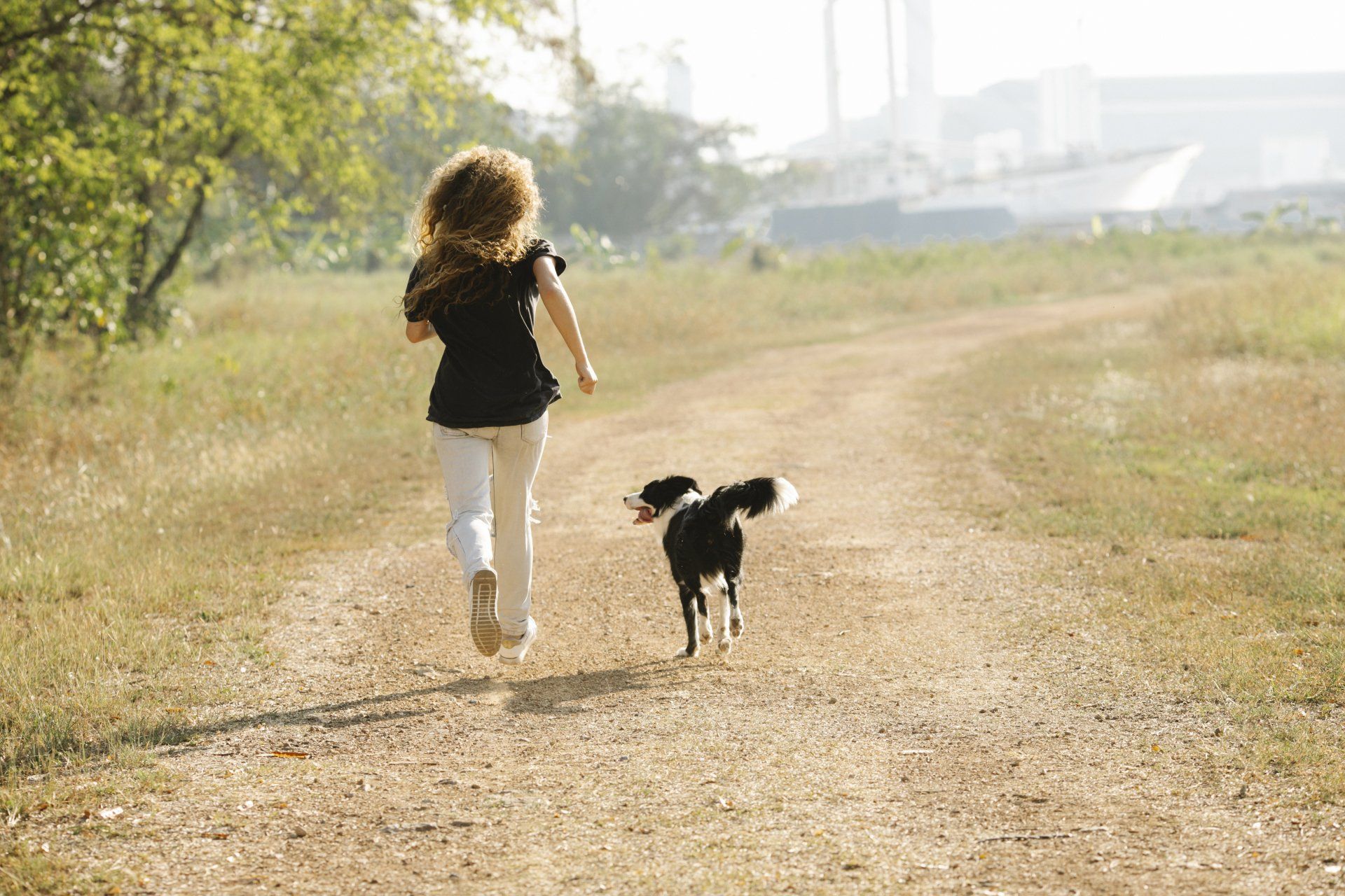 woman walking with healthy and happy dog on dirt road