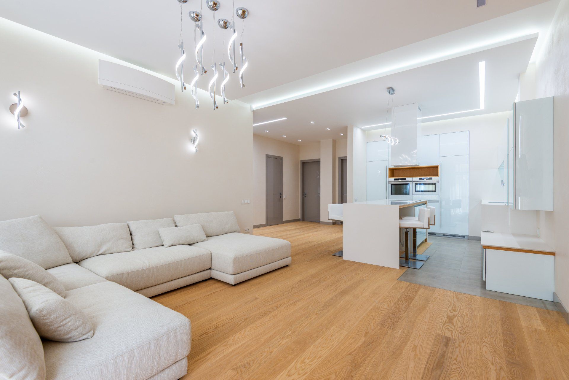 A living room with a white sectional couch and wooden floors.