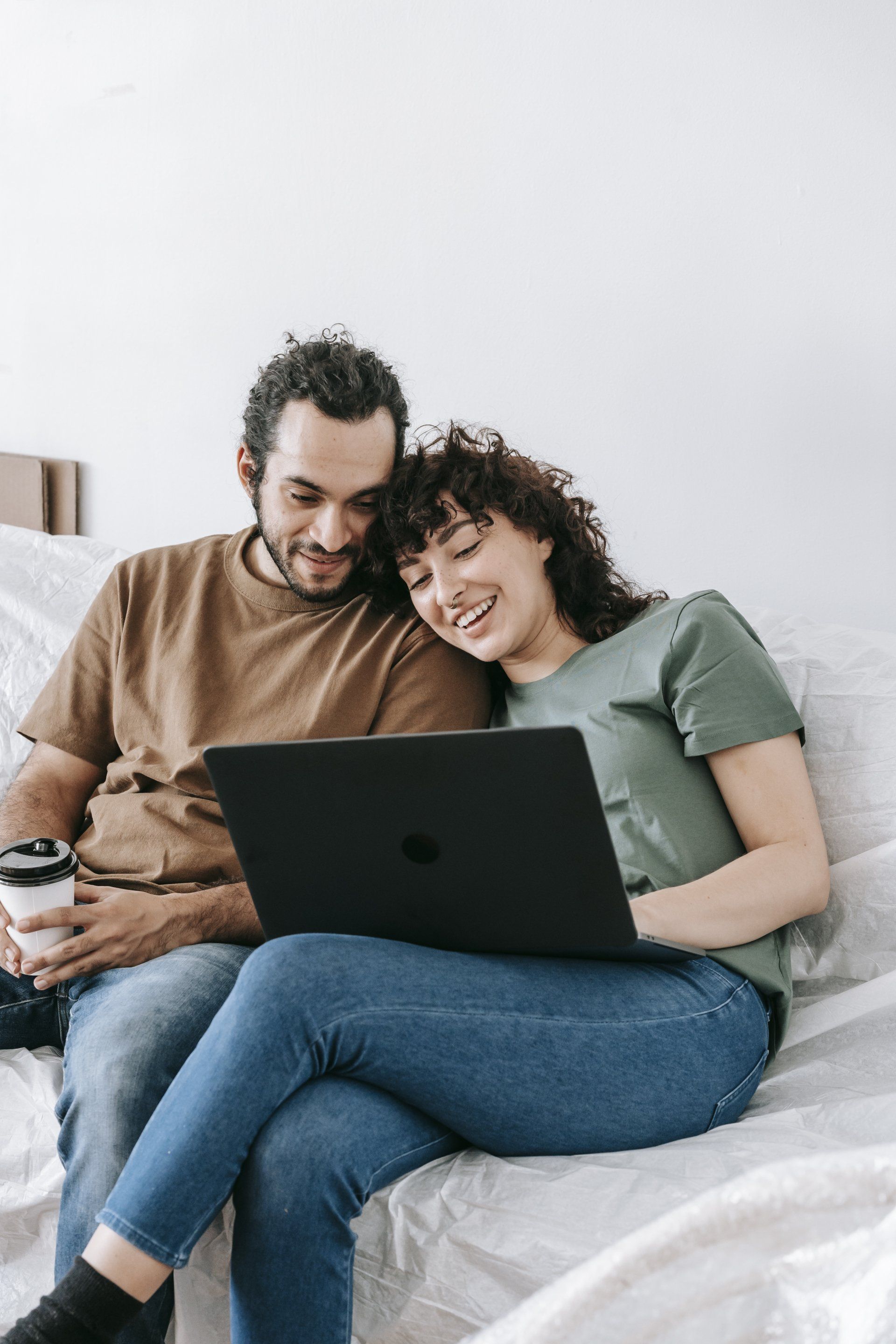 A man and a woman are sitting on a couch looking at a laptop.