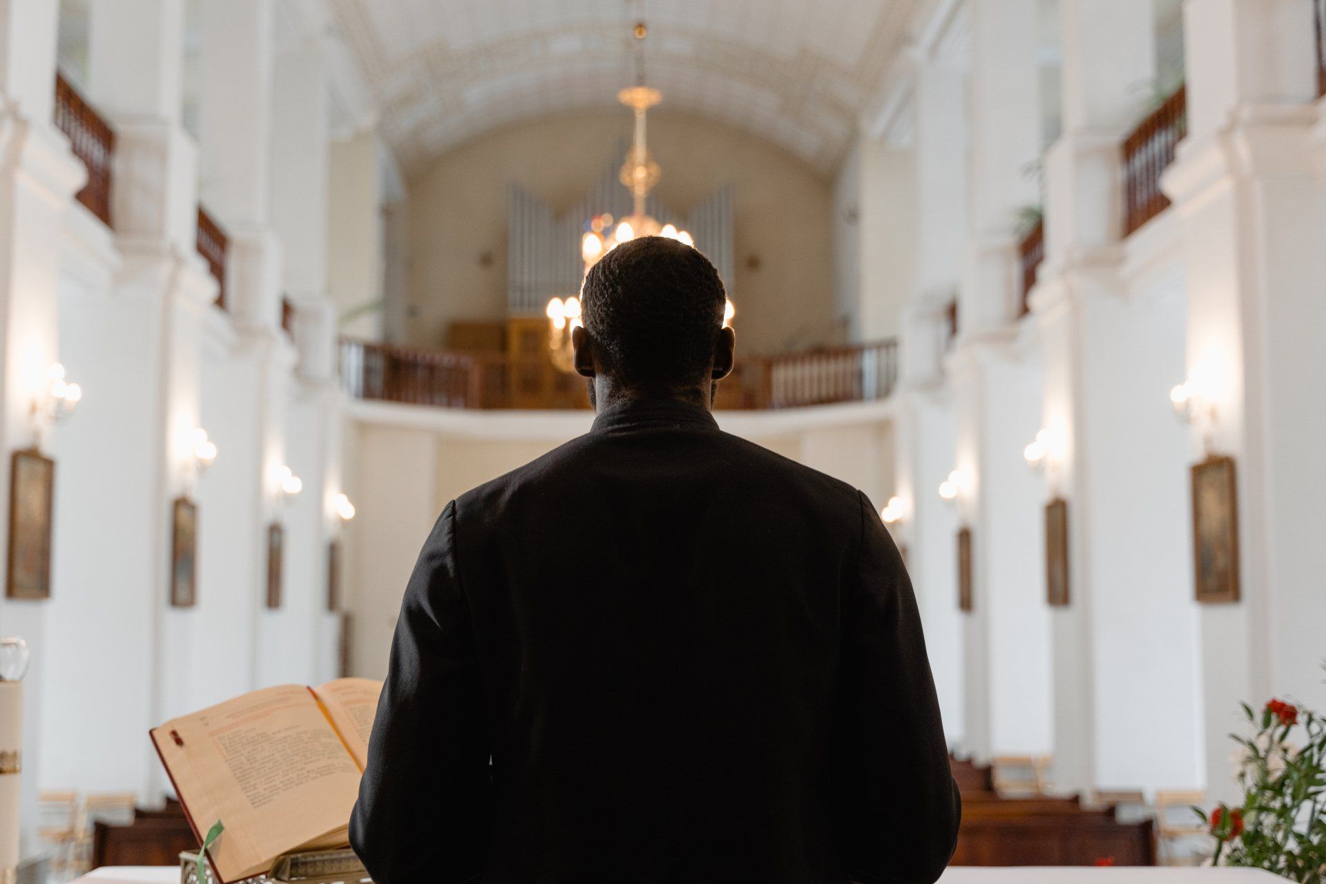 A man is standing in front of a podium in a church holding a book.
