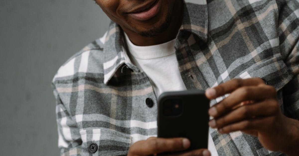 A man in a plaid shirt is using a cell phone.