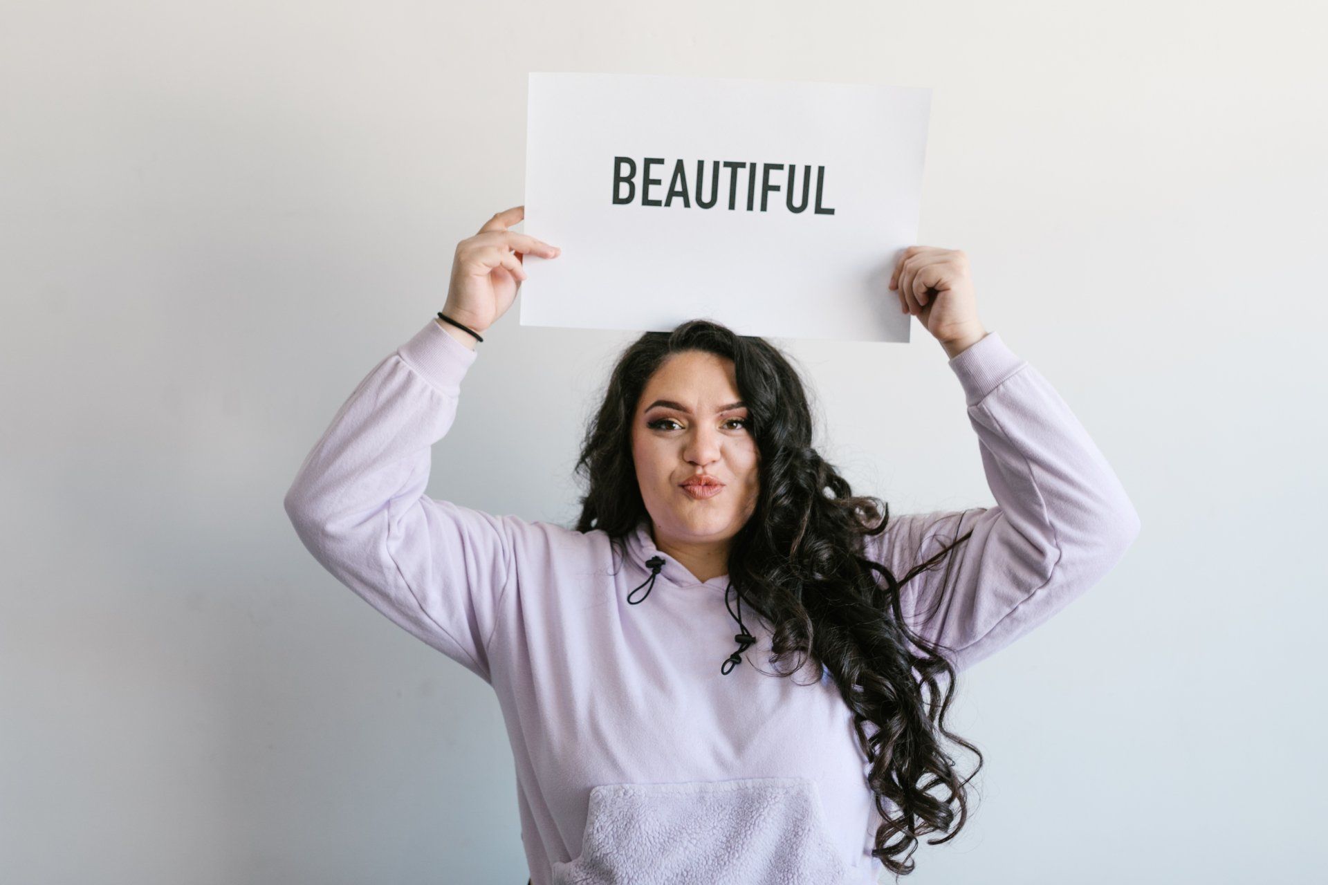 A woman is holding a sign that says beautiful over her head.