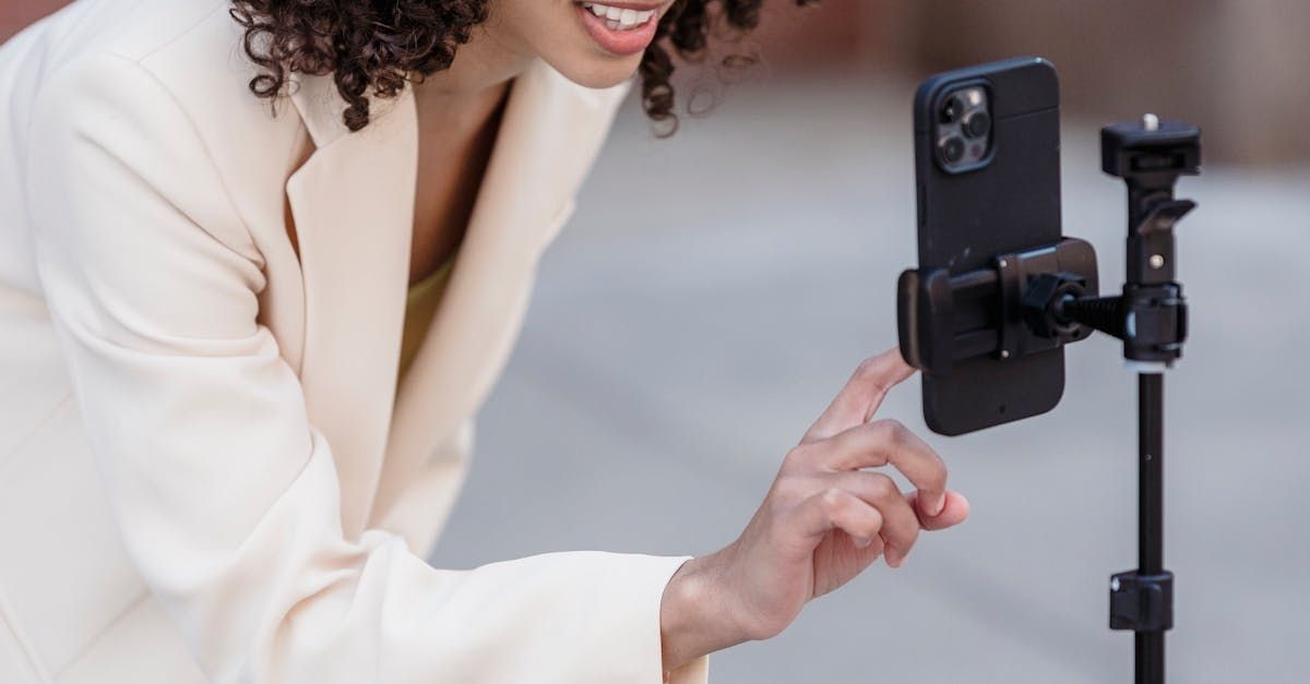 A woman is taking a selfie with her cell phone on a tripod.