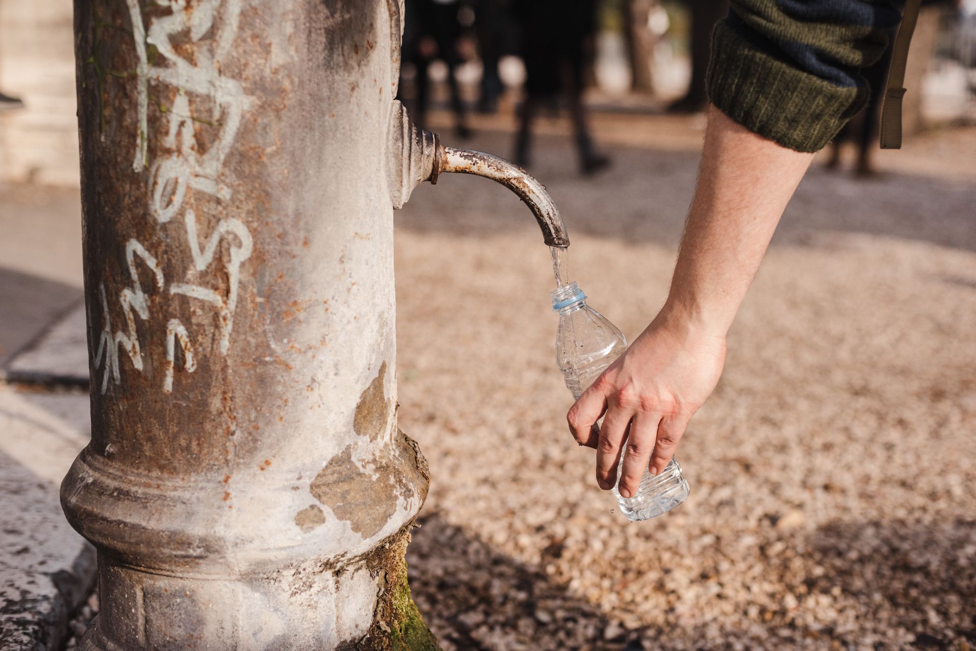 A person is pouring water from a faucet into a plastic bottle.