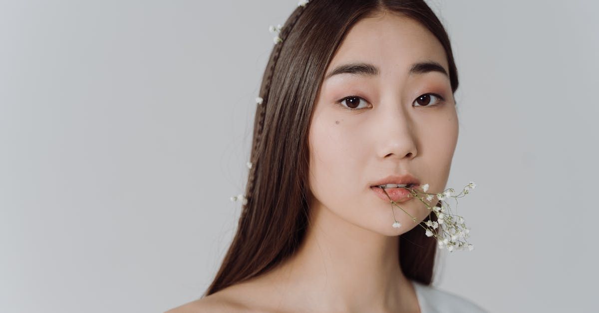 An Asian woman is holding a flower in her mouth.