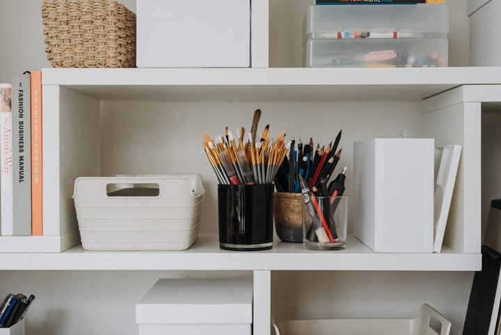 A shelf filled with books , boxes , and pencils.