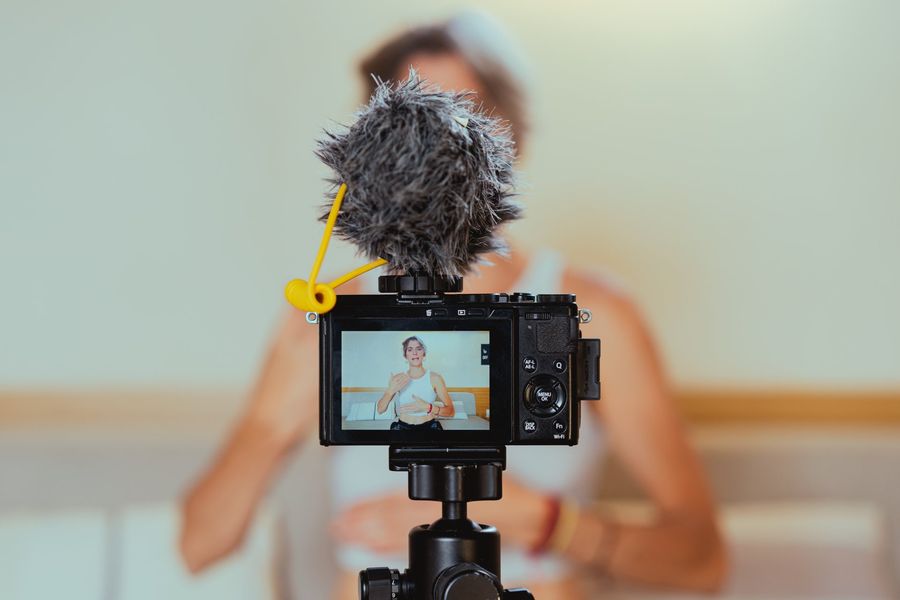 A woman is sitting in front of a camera with a microphone attached to it.