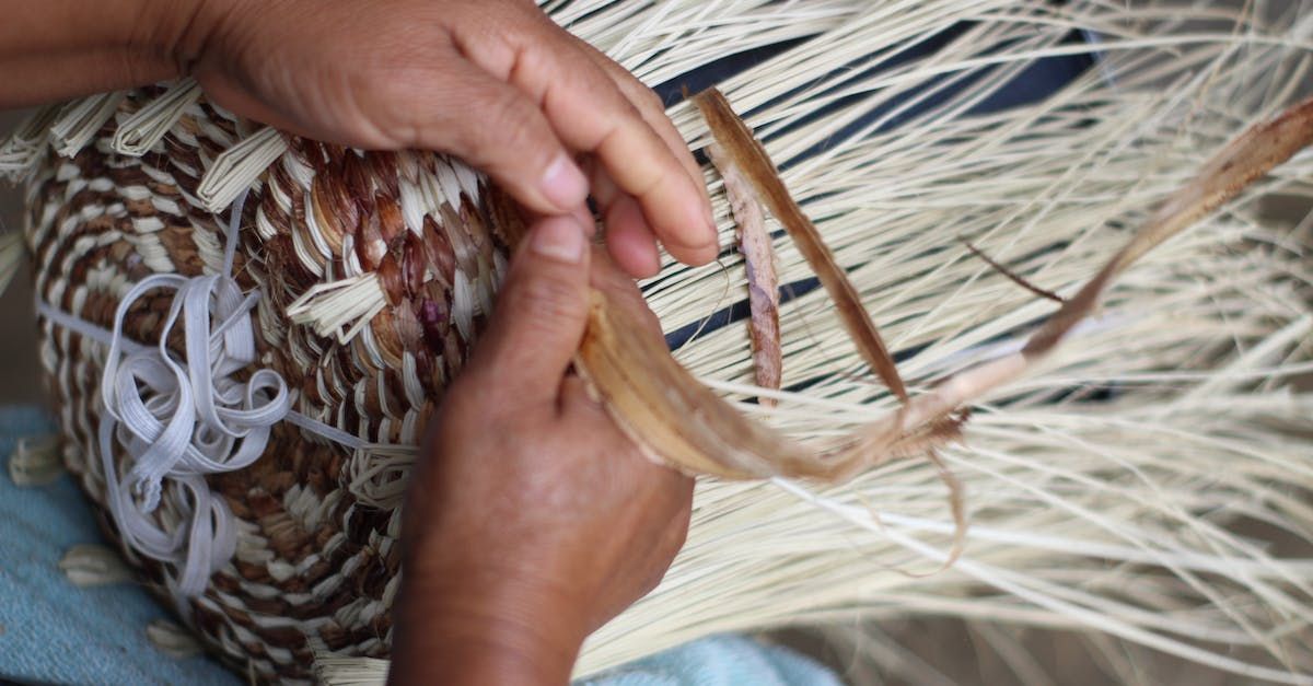 A person is making a hat out of straw.