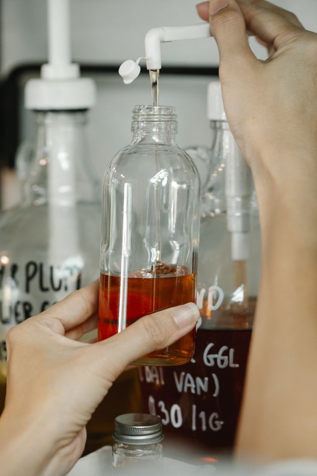 A person is pouring liquid into a glass bottle.