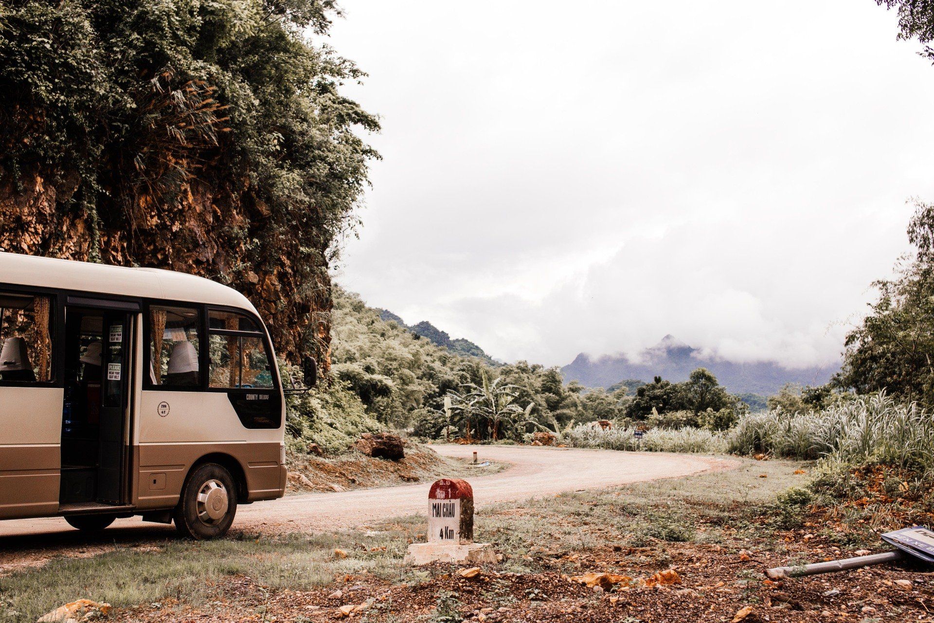 An RV bus stationed on the side of the road, in the mountains.
