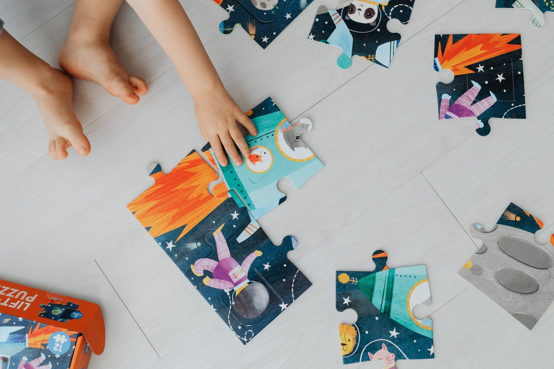 Un enfant joue avec un puzzle sur le sol.