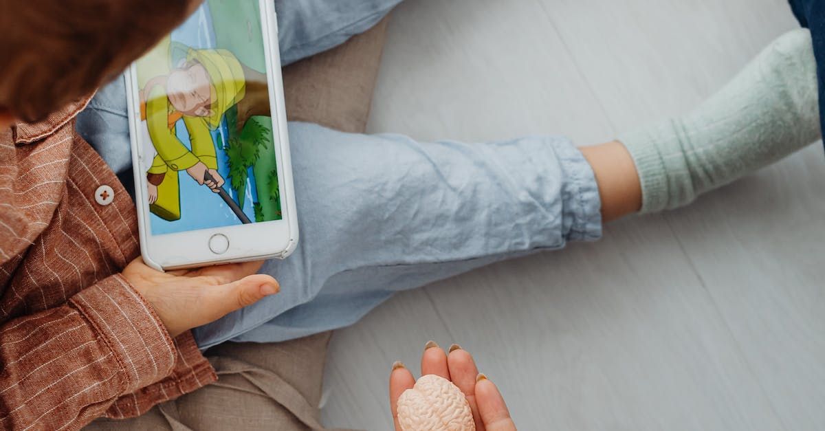 A person is holding a cell phone next to a child.