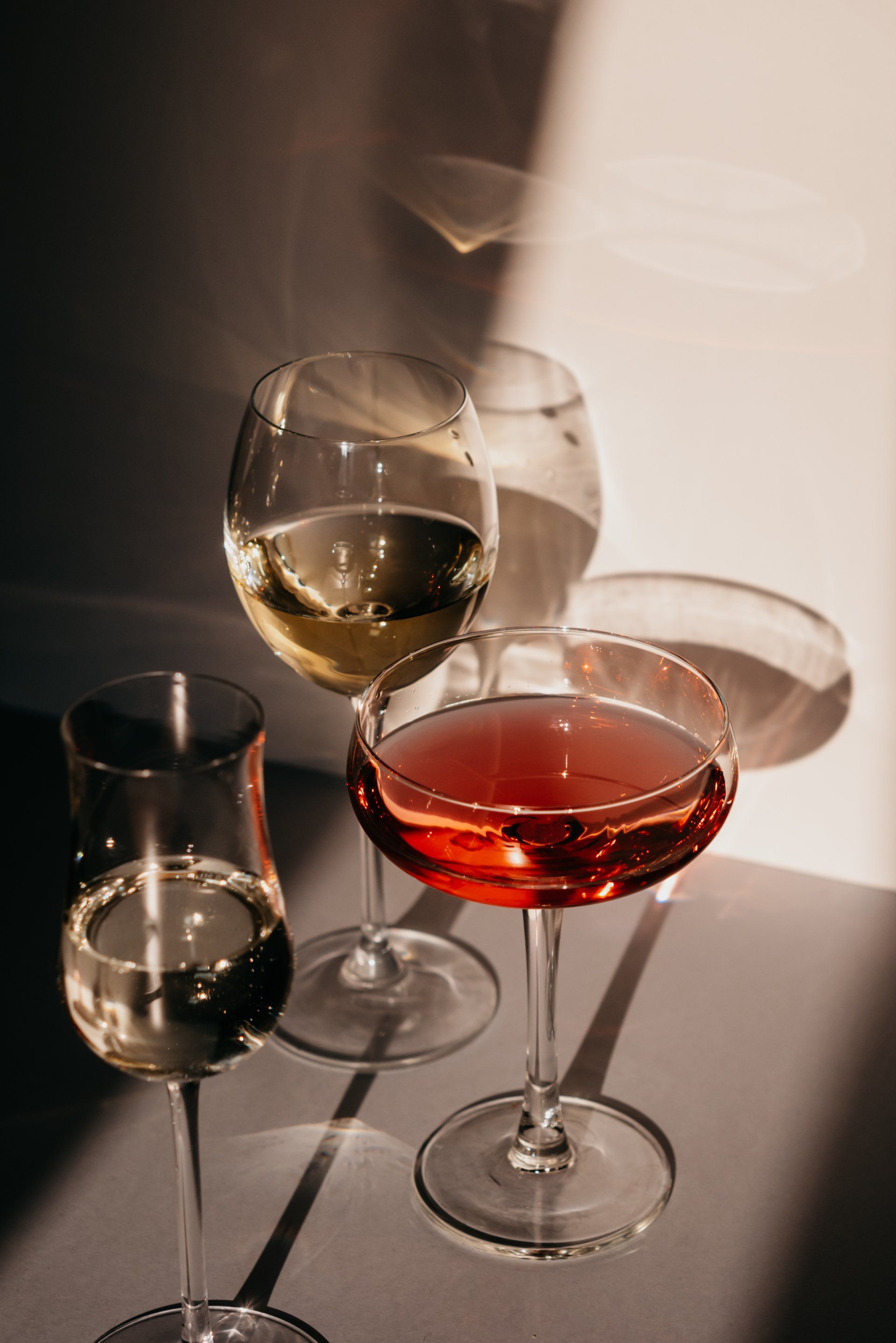 Three wine glasses filled with different types of wine are sitting on a table.