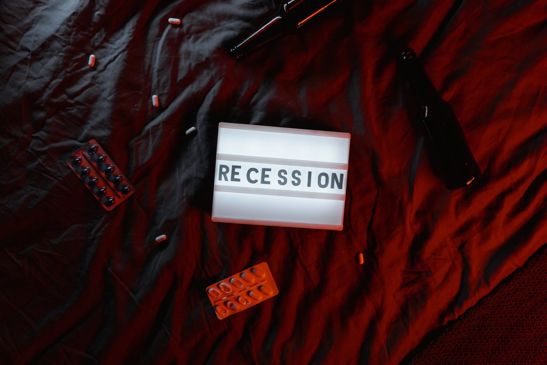 A light box with the word recession written on it is laying on a bed.